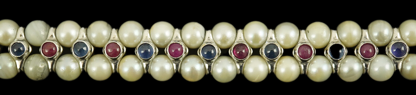 A late 20th century 18k white gold and two row cultured pearl bracelet, set with single row of cabochon rubies and sapphires